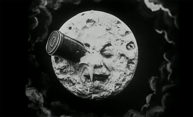 Black and white image from the film Le Voyage dans la Lune: a large spacecraft capsule has crashed onto the moon, directly into the face of "the man on the moon"